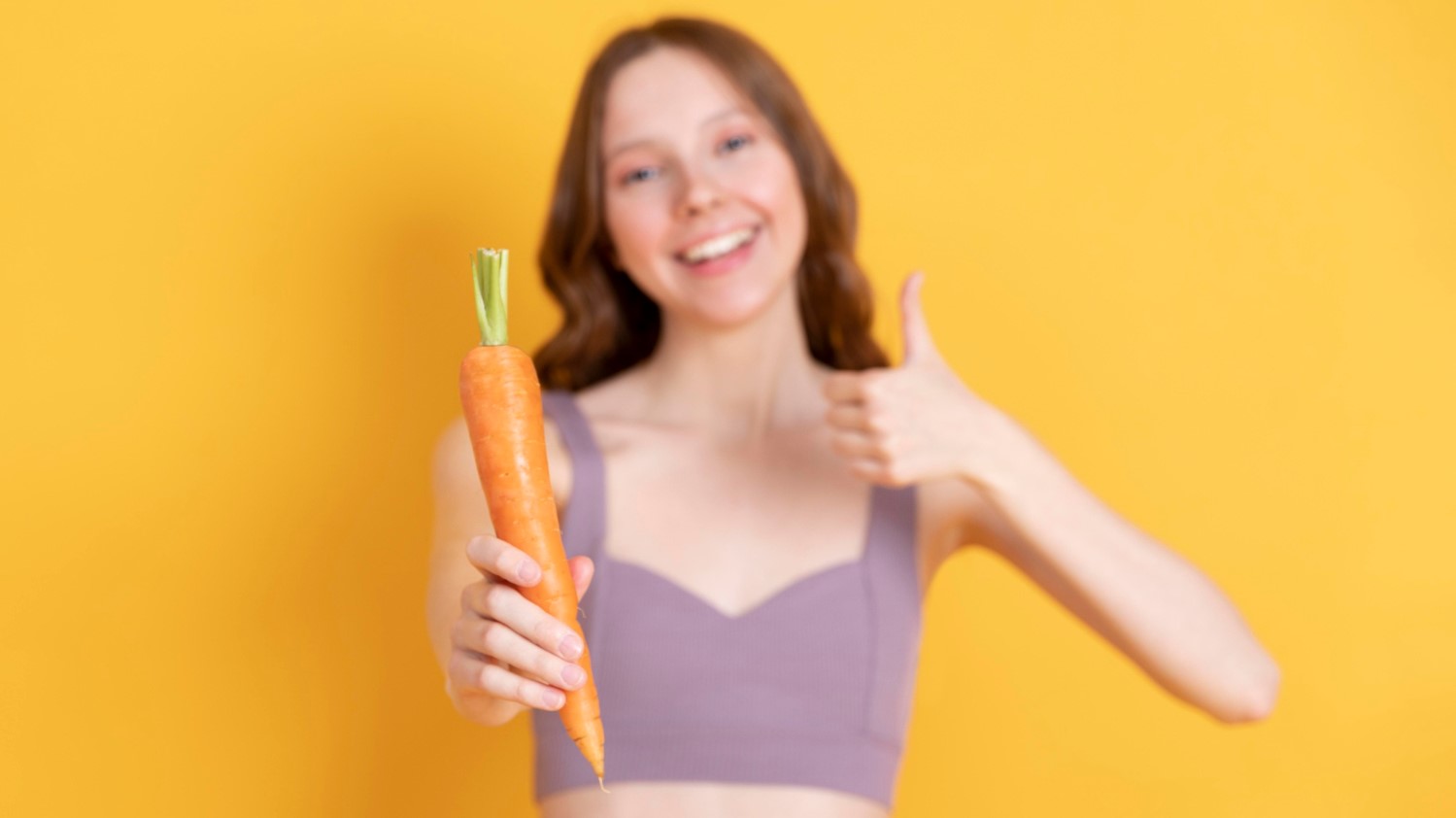 Девушка держит в руке морковь